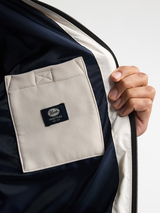 Binnenkant van een beige jas met donkerblauwe voering en een beige binnenzak met Petrol Industries label.