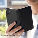 Man houdt zwarte lederen book case open, op maat gemaakt voor telefoon.