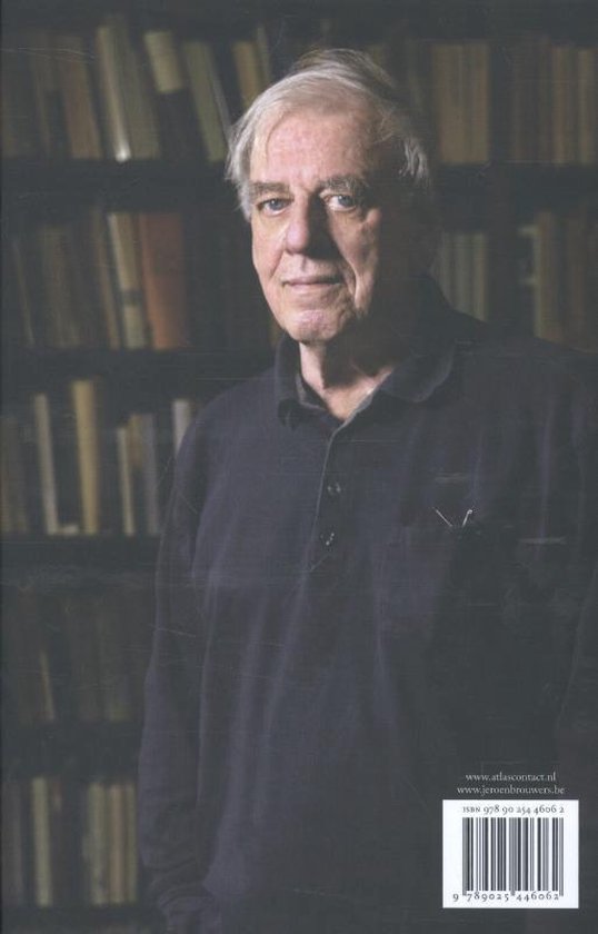 Portret van Jeroen Brouwers, staand voor een boekenkast.