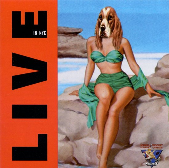Albumcover met 'LIVE IN NYC' in grote zwarte letters op een oranje achtergrond. Rechts een pin-up meisje in bikini met een hondenhoofd.