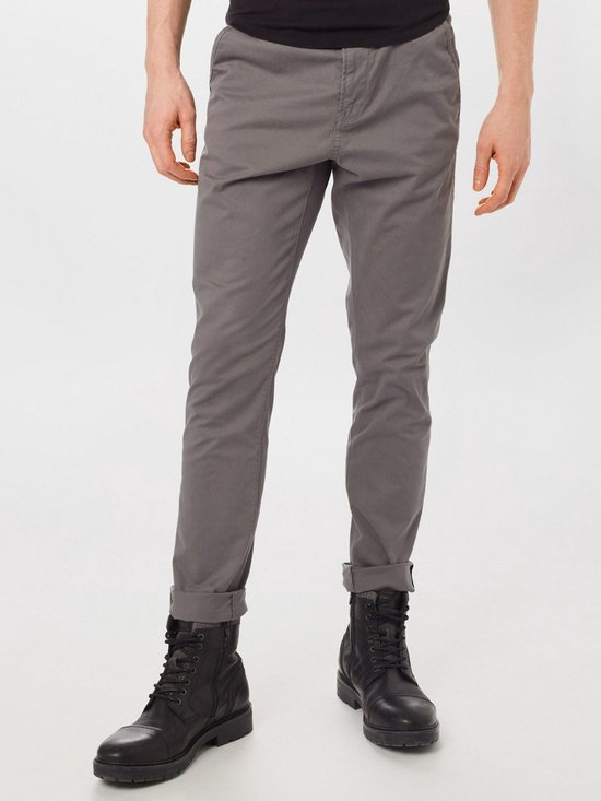 Voorkant van grijze chino broek met omgeslagen broekspijpen en zwarte laarzen.