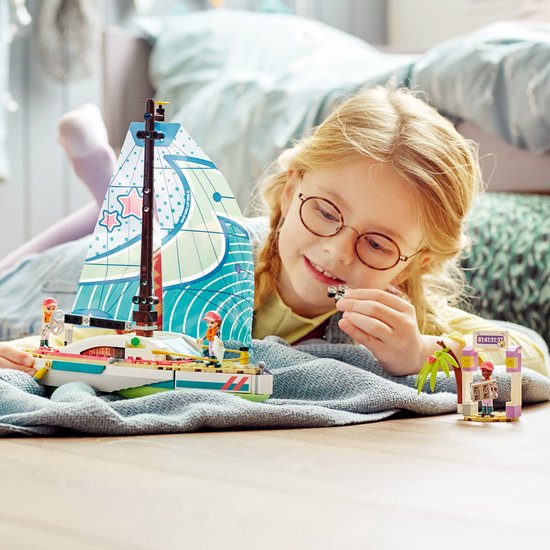 Een meisje met bril kijkt naar de LEGO Friends zeilboot set met drie poppetjes en racepoort.