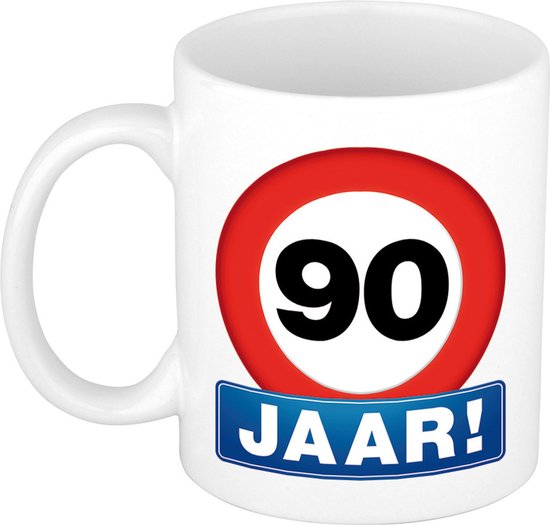Tasse blanche avec un panneau de signalisation rouge "90" et en dessous un panneau bleu "90 JAAR!"