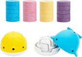 Stapels gekleurde bruistabletten en een gele kogelvis met een blauwe walvis die aan een dispenser vastzit.