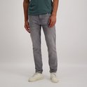 Man met grijze slim fit spijkerbroek en witte sneakers.