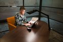 Man in geruit overhemd werkt aan laptop met bureaulamp.