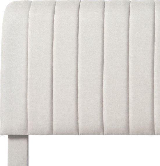 Gros plan d'une tête de lit rembourrée à nervures verticales en tissu beige.