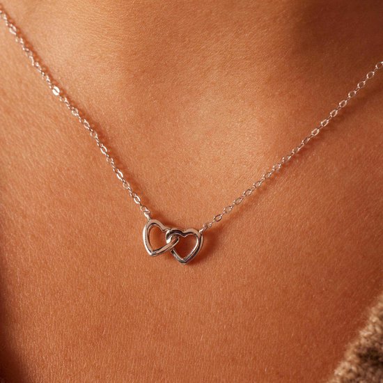 Zilverkleurige ketting met twee in elkaar grijpende hartjes aan een dunne ketting.
