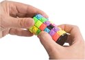 Een veelkleurige, cilindervormige draaipuzzel met blokjes in geel, groen, paars, roze en blauw, vastgehouden in handen.