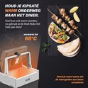 Een geopende koelbox met een verwarmde schotel met kipspiesjes en brood ernaast, op een donkere achtergrond.