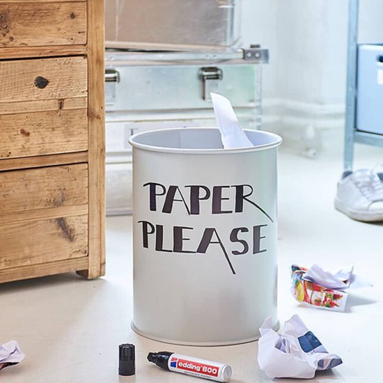 Zwarte edding 800 permanente marker op de vloer bij een prullenbak met tekst 'PAPER PLEASE'.