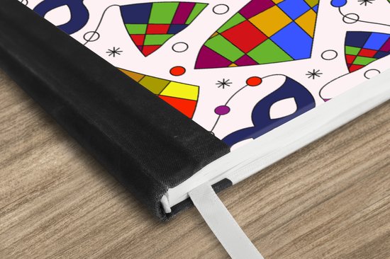 Détail de la couverture noire et de l'imprimé de masques de carnaval et de losanges d'un carnet.