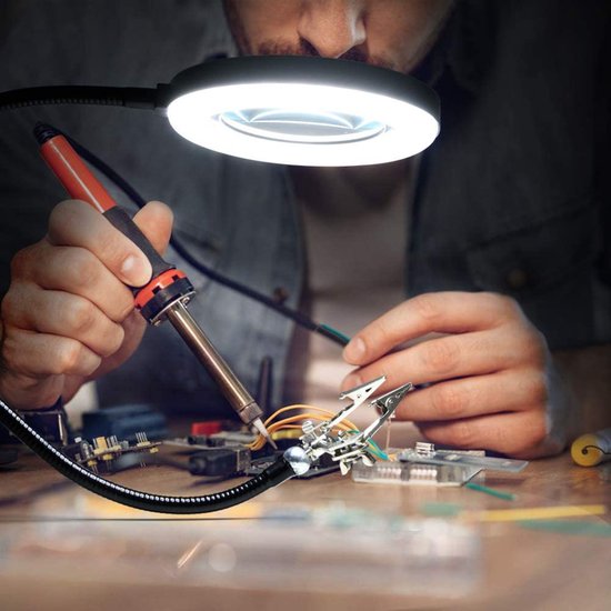 Man met soldeerbout en vergrootglas met LED-ringverlichting