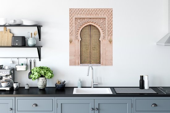Une porte marocaine couleur sable avec des détails dorés et une sculpture sur pierre complexe, accrochée au-dessus d'un comptoir de cuisine.
