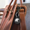 Zwarte Belkin AirTag houder met sleutelhanger aan een bruine leren tas.