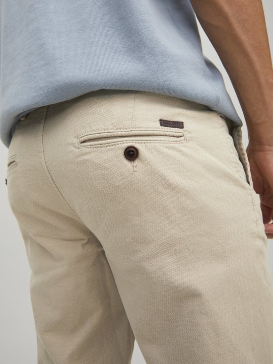 Detail van de achterkant van beige chino met knoopzak.