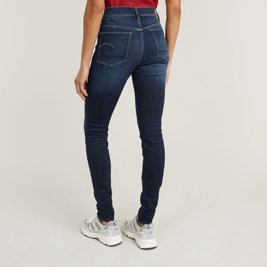 La mannequin porte un jean skinny en denim foncé, le dos montre le logo G-Star sur la poche droite.