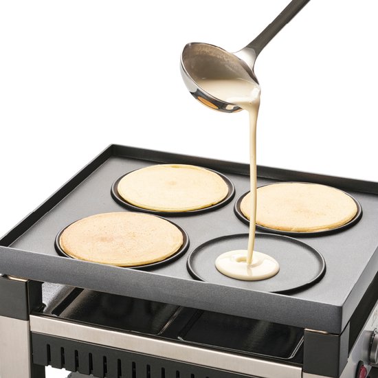 Pannenkoeken bakken op een zwarte grillplaat met vier ronde vormen.