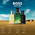 Drie BOSS flessen: Eau de Toilette, Eau de Parfum Citrus en Parfum in een woestijnlandschap.