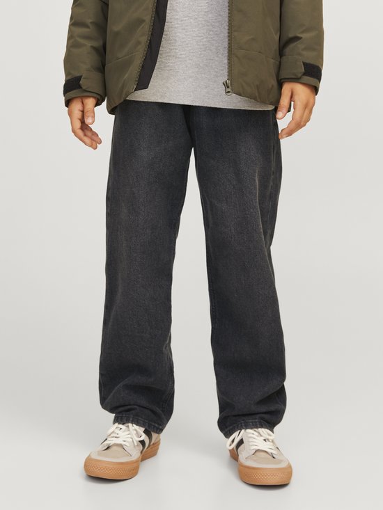 Zwarte jeans met rechte pijpen gedragen door een jongen met een olijfgroen jasje.