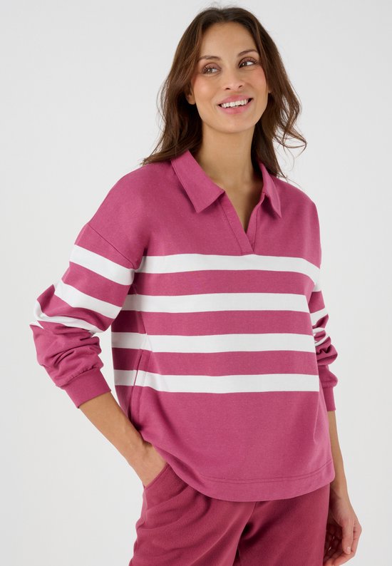 Femme souriante portant un sweatshirt en polaire à rayures roses et blanches.