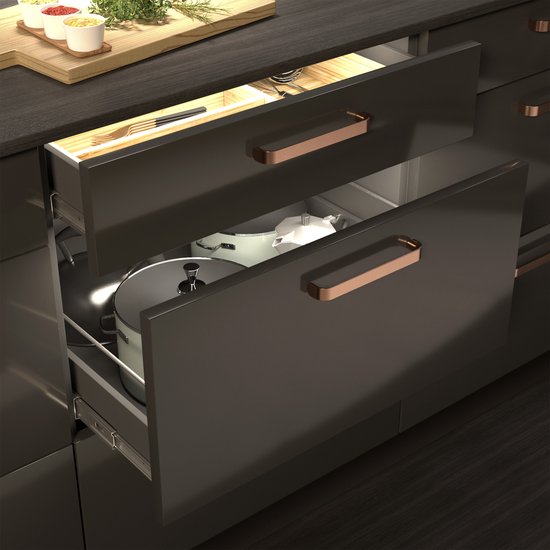 Keukenkast met een open lade voorzien van koperkleurige grepen. In de lade liggen keukengerei en een pan.