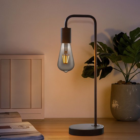 Ampoule LED E27 en verre fumé gris dans une lampe de table moderne, en lumière tamisée.