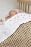 Slapende baby onder een wit dekentje met roze hartjes.