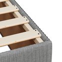 Gros plan du bord textile gris clair d'un sommier à lattes en bois.