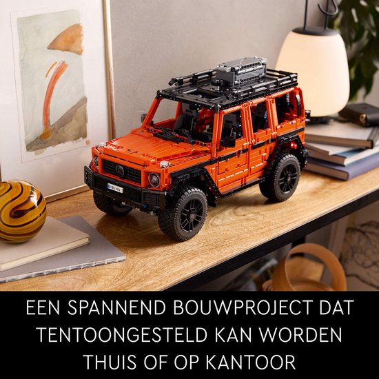 Oranje LEGO Mercedes-Benz G 500 op een houten tafel, naast decoratie. "Een spannend bouwproject dat tentoongesteld kan worden thuis of op kantoor."