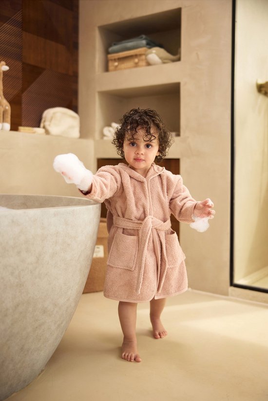 Peignoir rose à capuche, porté par un enfant près d'une baignoire.