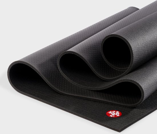 Zwarte Manduka yogamat, deels opgerold, met rood logo.
