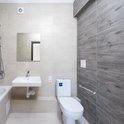 Moderne badkamer met een betegelde muur en douchezitje.