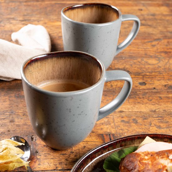 Twee grijze mokken met koffie op een houten tafel. Mokken hebben bruine binnenkant.