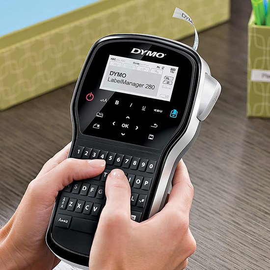 Handen die de zwarte DYMO LabelManager 280 labelprinter vasthouden en bedienen met AZERTY-toetsenbord.