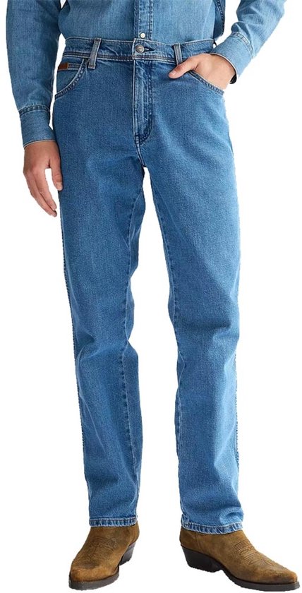 Homme, longueur 3/4, portant un jean et des bottes, main dans la poche, fond blanc.