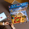 Een open LEGO City adventskalender met een winterlandschap, speelfiguren en voertuigen. Een kind bouwt aan een trein.