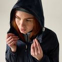 Close-up van een roodharige vrouw die de capuchon van haar donkerblauwe jas vastpakt.