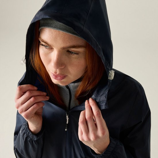 Close-up van een roodharige vrouw die de capuchon van haar donkerblauwe jas vastpakt.