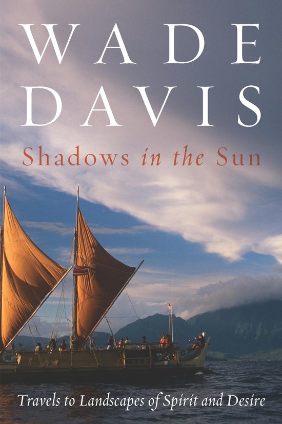 Boek "Shadows in the Sun" van Wade Davis. Zeilboot met oranje zeilen op water, met bergen op de achtergrond. Tekst: "WADE DAVIS Shadows in the Sun Travels to Landscapes of Spirit and Desire"