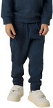 Onderlichaam van een jongen in een donkerblauwe joggingbroek en witte sneakers.