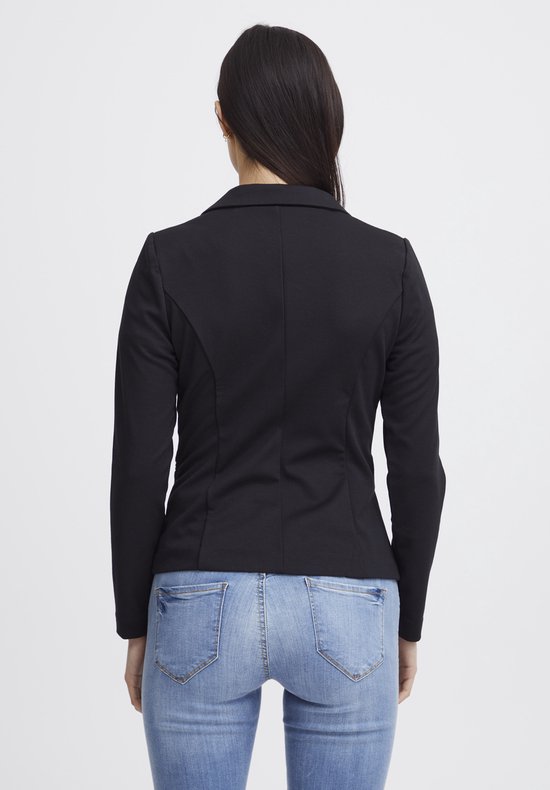 Zicht op de achterkant van een vrouw in een zwarte getailleerde blazer en spijkerbroek.