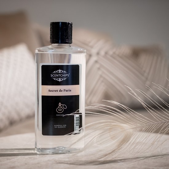 Fles "Scentchips" geurolie "Secret de Paris" met zwarte dop op tafel.