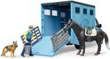 Lichtblauwe Bruder paardenwagen met open laadklep. Een man met emmer en een hond staan ernaast, een paard op de laadklep.