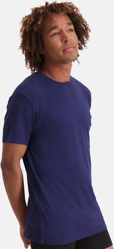 Jonge man met krullend haar, kijkt omhoog, draagt een navy blauw t-shirt