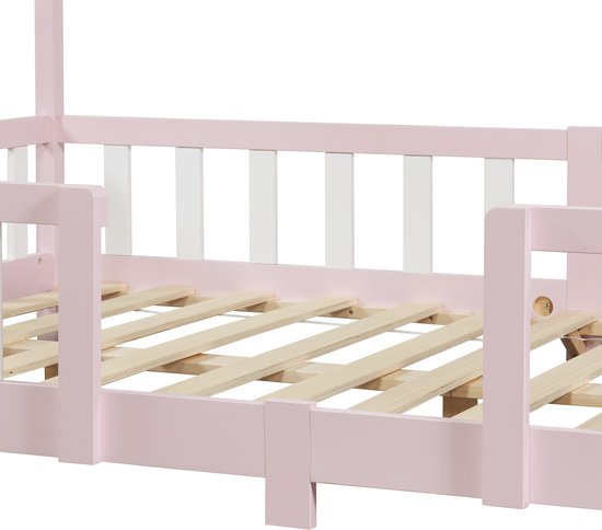 Close-up van het roze kinderbed frame met witte spijlen en houten lattenbodem.