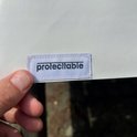 Étiquette avec le texte 'protecttable' tenue par une main.