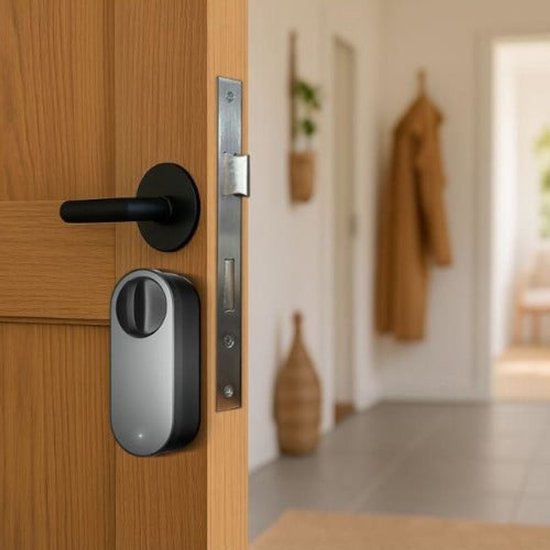 Zwart Aqara slim deurslot met cirkelvormig handvat, op een houten deur geplaatst naast deurbeslag.