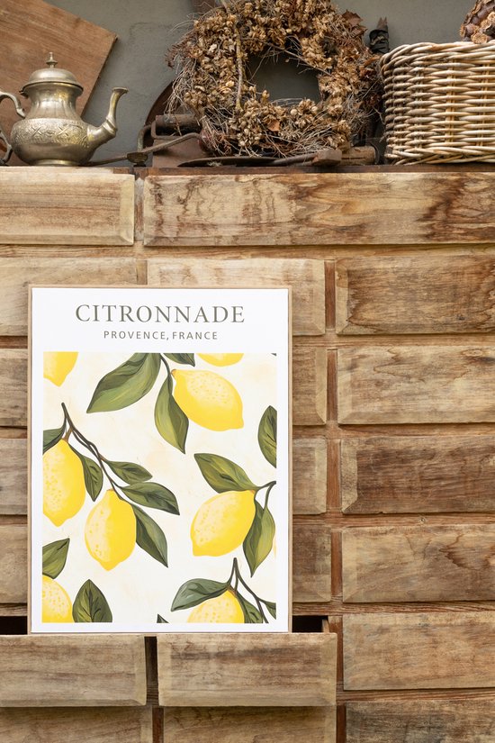 Toile peinte avec des citrons et des feuilles dans un cadre en bois, suspendue à un mur en bois.