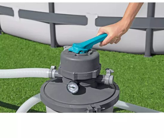 Hand bedient de turquoise hendel bovenop een grijze zandfilterpomp.